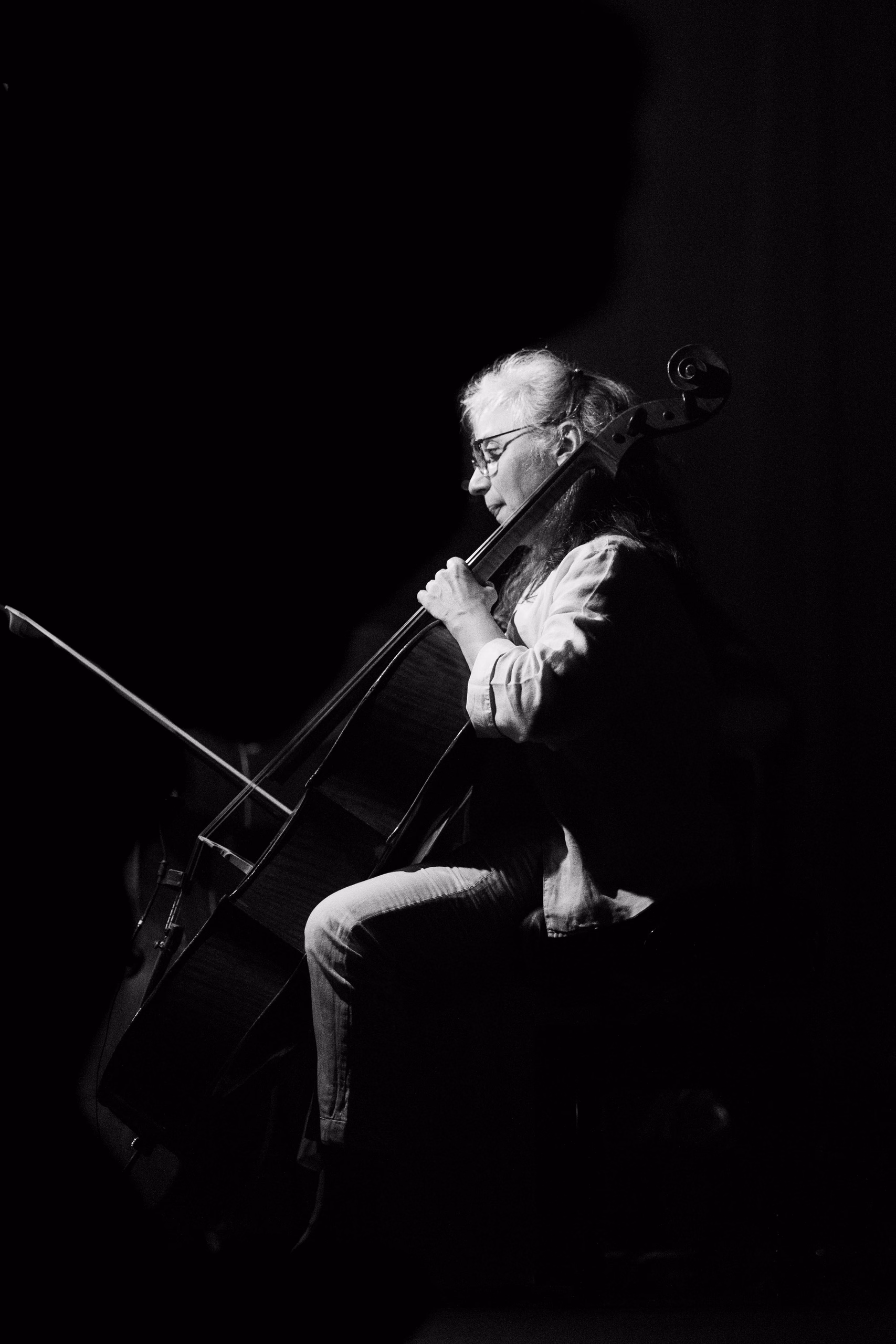 Violoncelliste de profil jouant dans la pénombre, en noir et blanc