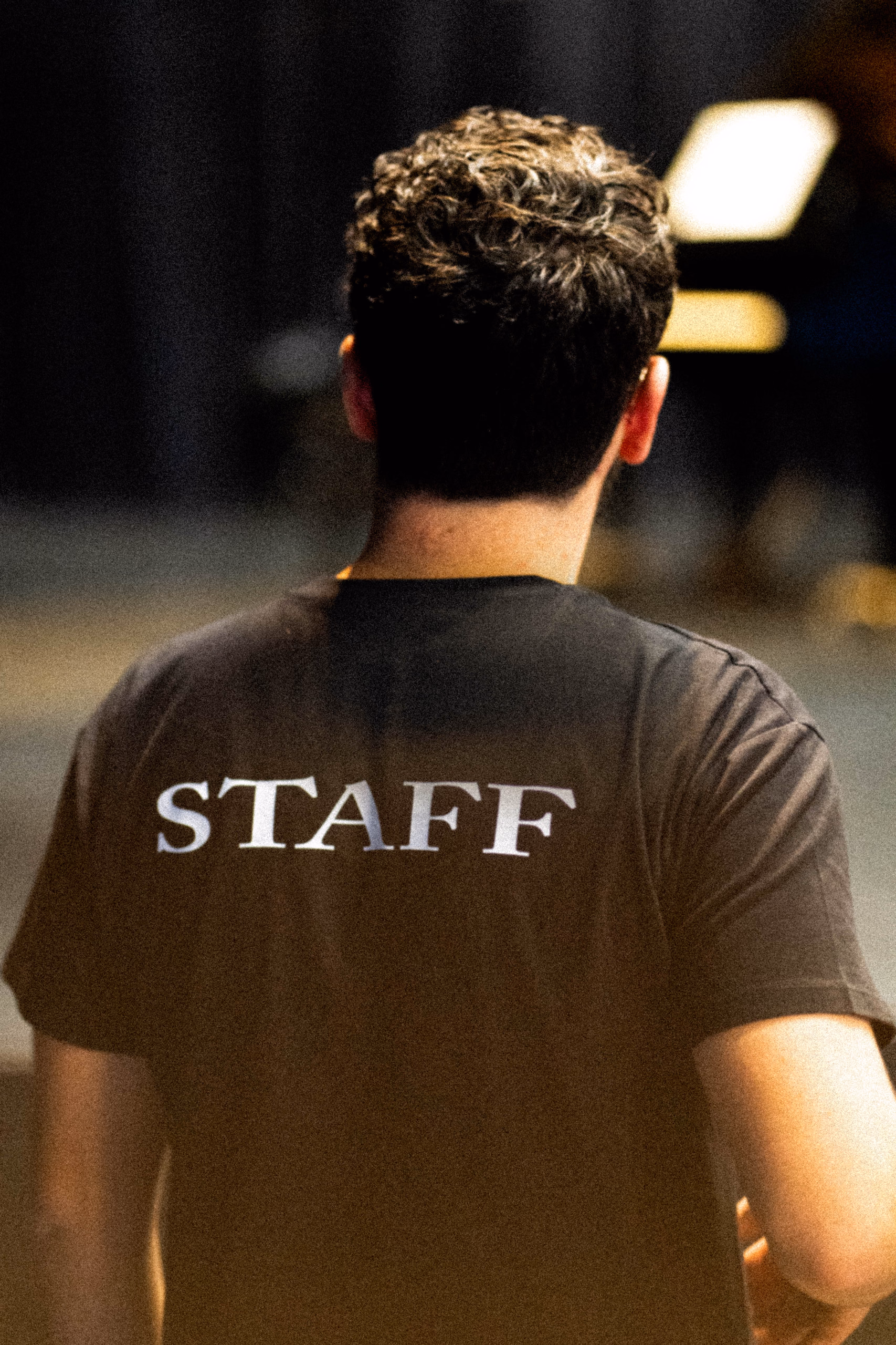 De dos, membre de l'équipe en t-shirt noir marqué « STAFF »